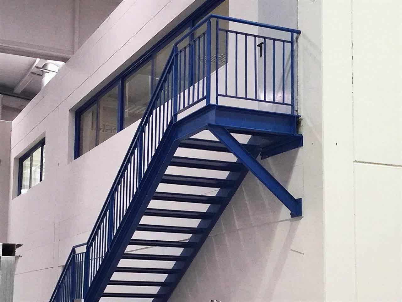 Escalera metálica exterior azul montada en un edificio industrial de Pontevedra